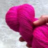 Détail d'Un écheveau de laine à chaussettes rose fluo soutenu posé sur un fond de fausse fourrure blanche