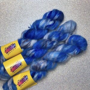Trois écheveaux de suri silk cloud posés sur un fond gris clair à paillettes
