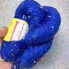 un écheveau de laine bleu électrique posé sur un fond gris clair à paillettes