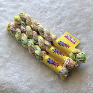 Trois écheveaux de Sugar Sprinkles, un coloris teint à la main par Madame Guillotine comprenant des speckles jaune et rose fluo et bleu vif