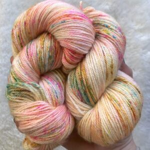 Un écheveau en BFL soie et cachemire teint à la main dans les tons de beige, champagne avec des speckles rose bleu et vert