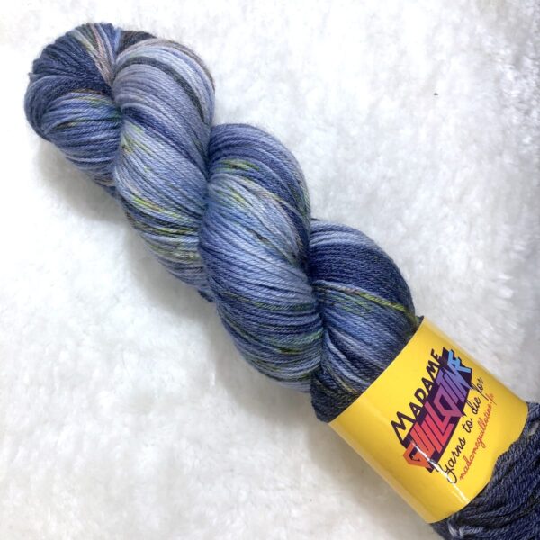 Un écheveau de laine teinte à la main dans des coloris variés de bleu marine, chocolat et vert fluo sur de la fausse fourrure blanche