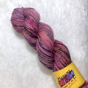 Un écheveau de laine teinte à la main dans des coloris variés de rose, fuchsia et gris métal sur de la fausse fourrure blanche