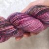 Un écheveau de laine teinte à la main dans des coloris variés de rose, fuchsia et gris métal sur de la fausse fourrure blanche