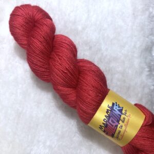 Un écheveau de laine teinte à la main dans un rouge vif posé sur de la fausse fourrure blanche