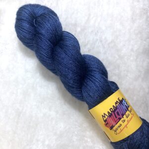 Un écheveau de laine teinte à la main dans un bleu marine posé sur de la fausse fourrure blanche