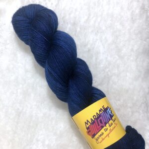 Un écheveau de laine teinte à la main dans un bleu marine posé sur de la fausse fourrure blanche